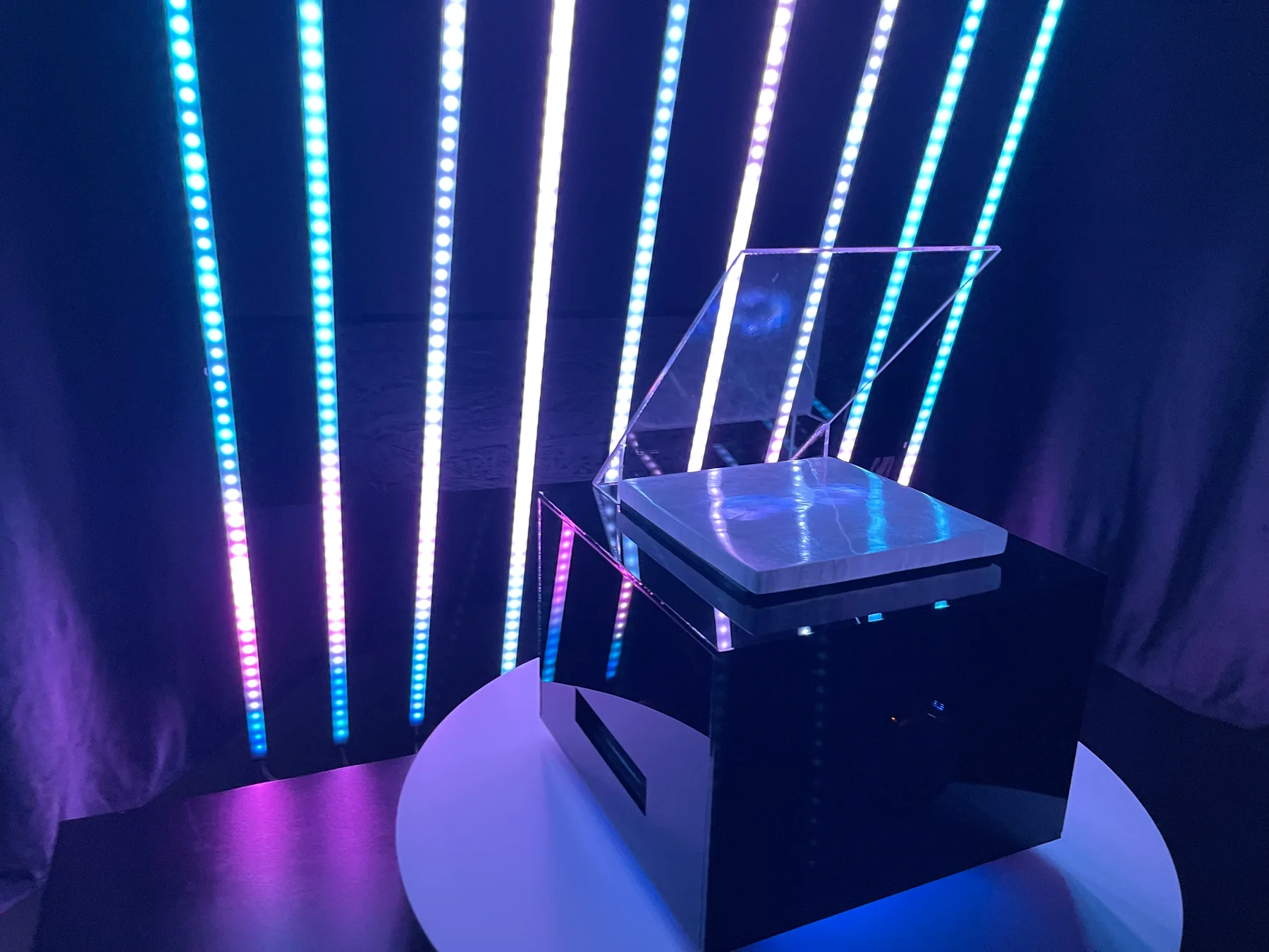 Prototyp obiektu na okrągłym podeście, na tle pionowych linii LED.