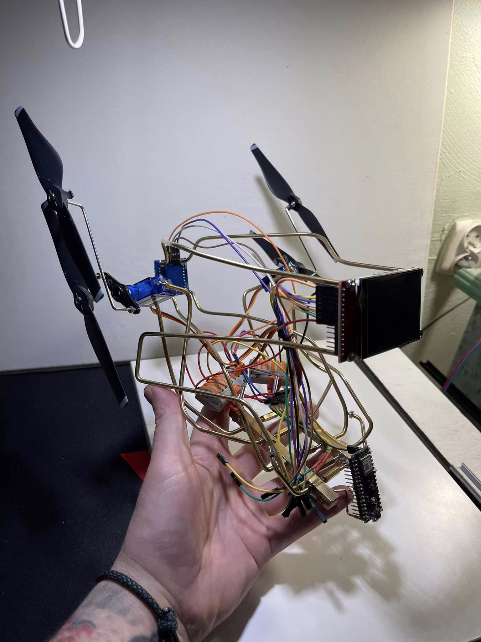 Dłoń trzymająca otwarty szkielet prototypu z mechaniką, ekranem i przewodami